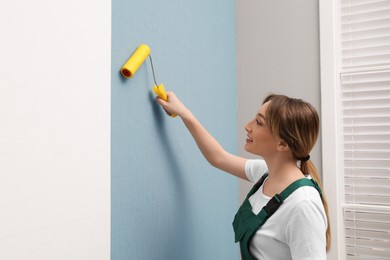 Photo of Worker hanging stylish wall paper sheet indoors