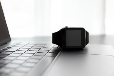 Photo of Modern stylish smart watch on laptop, closeup