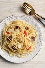 Delicious pasta with anchovies, tomatoes and parmesan cheese served on white wooden table, flat lay