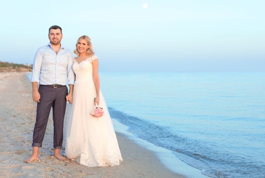 Photo of Wedding couple standing on beach. Space for text