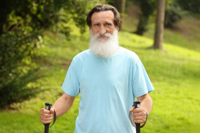 Photo of Senior man with Nordic walking poles outdoors