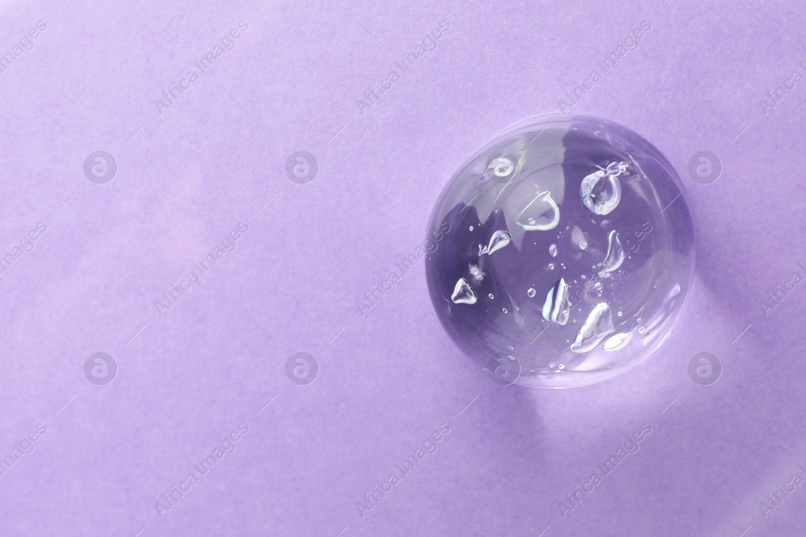 Photo of Clear cosmetic gel on violet background, top view. Space for text