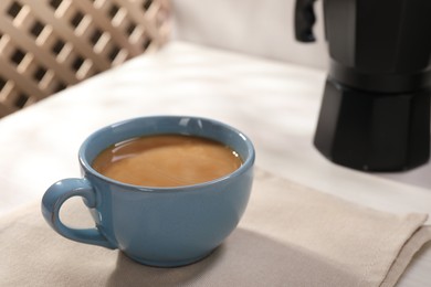 Delicious coffee in cup on white table, closeup. Space for text