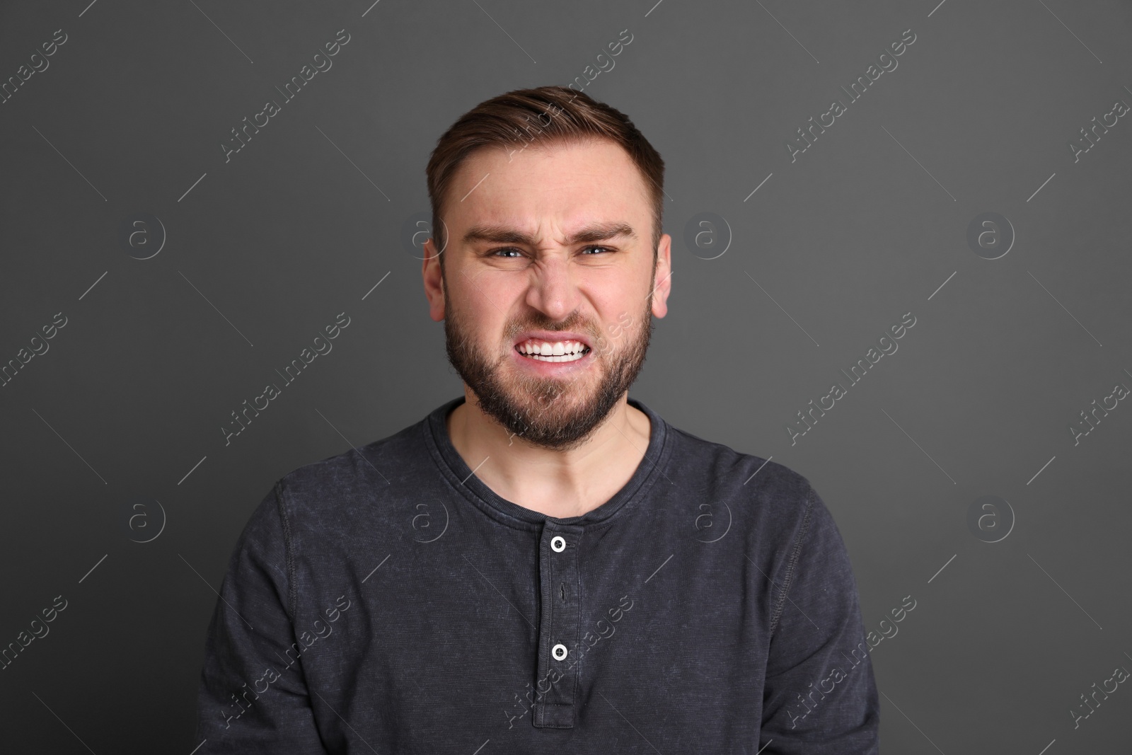 Photo of Portrait of angry young man on grey background. Personality concept