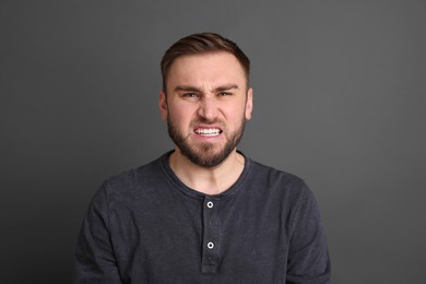 Photo of Portrait of angry young man on grey background. Personality concept