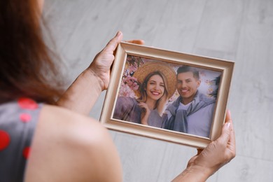 Photo of Woman holding framed photo of happy couple indoors, closeup