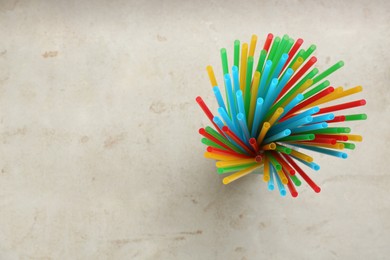 Photo of Colorful plastic drinking straws on grey stone table, flat lay. Space for text