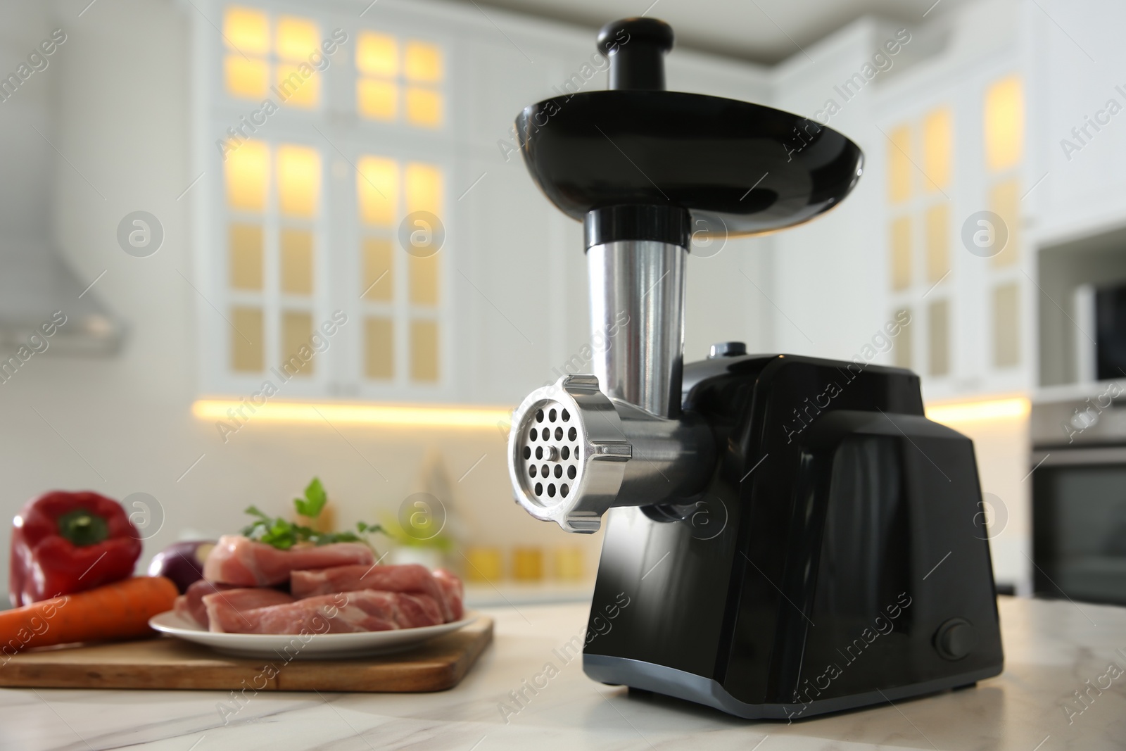 Photo of Modern meat grinder and products on white marble table in kitchen. Space for text