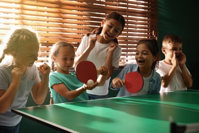 Photo of Cute happy children playing ping pong indoors