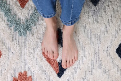 Woman on carpet with pattern at home, top view