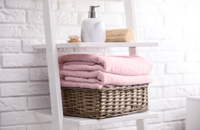 Photo of Basket with clean towels on shelving unit in bathroom