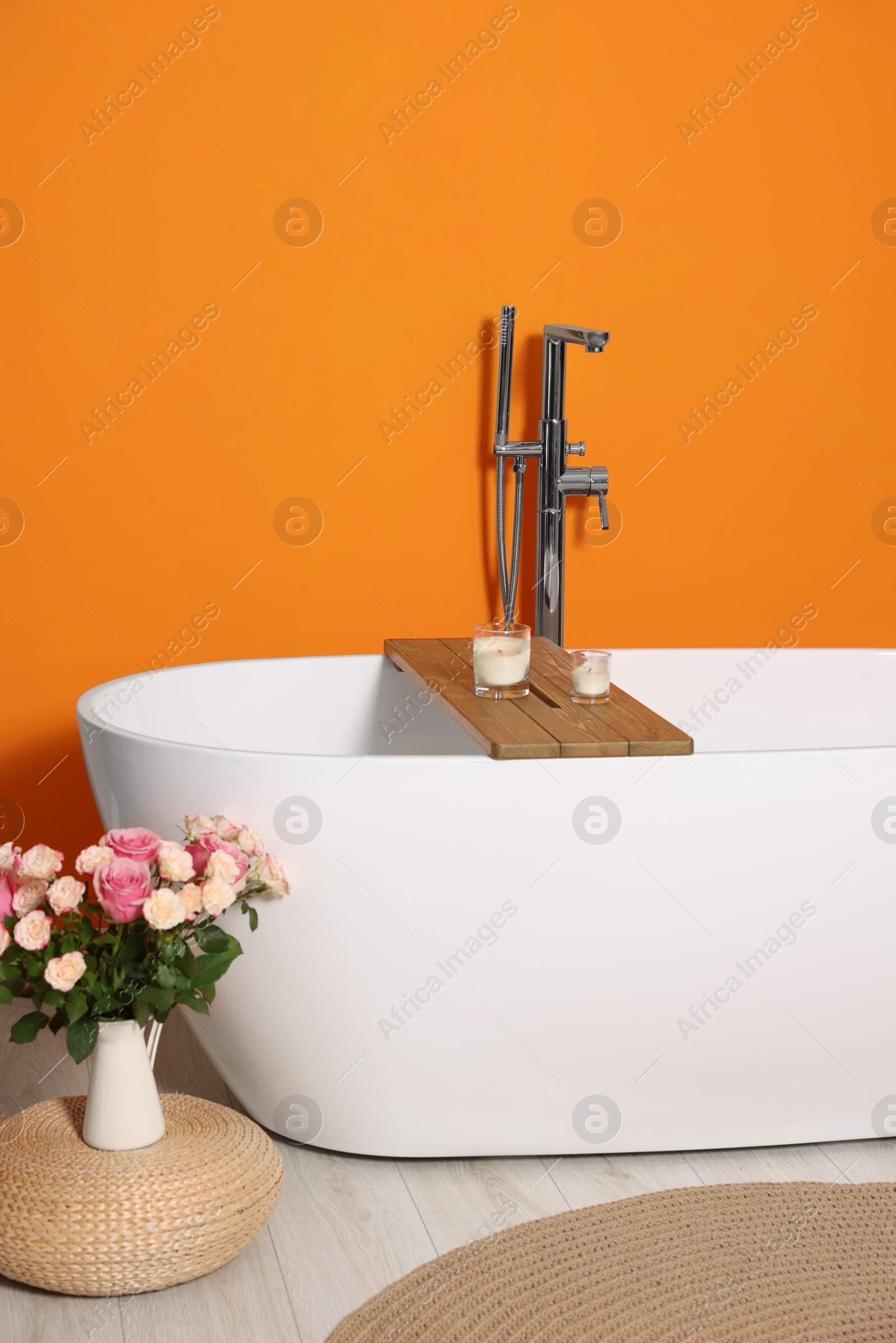 Photo of Stylish bathroom interior with ceramic tub and beautiful bouquet of roses