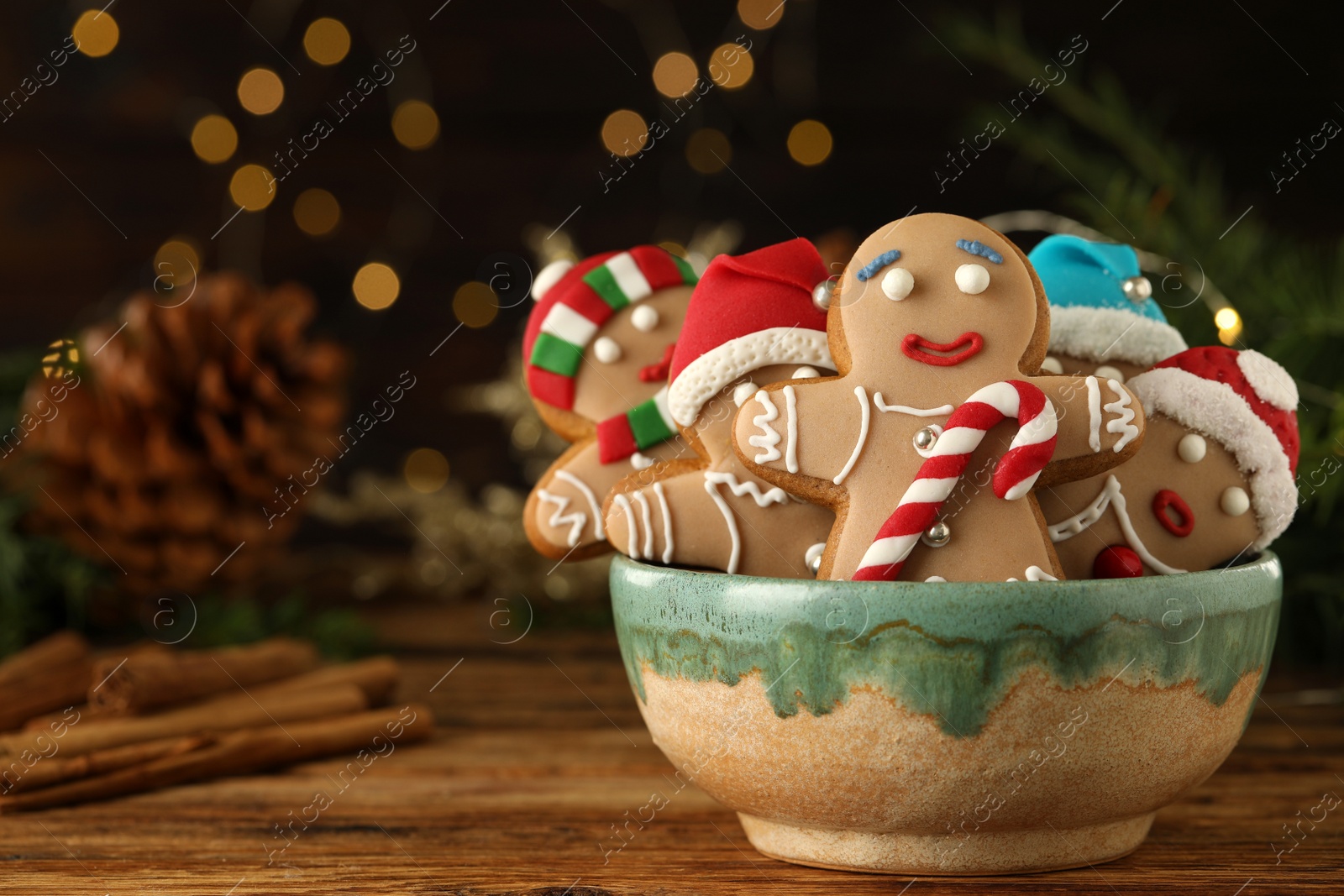Photo of Delicious homemade Christmas cookies in bowl on wooden table against blurred festive lights. Space for text