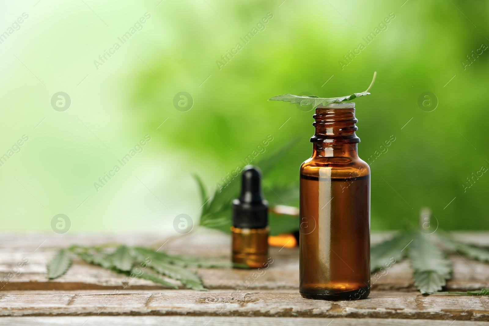 Photo of Bottle with hemp extract on table and space for text against blurred background