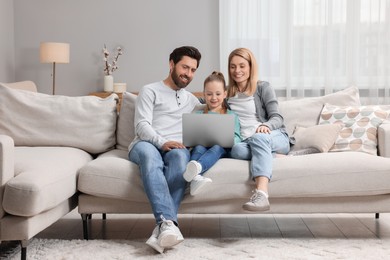 Photo of Happy family with laptop on sofa at home