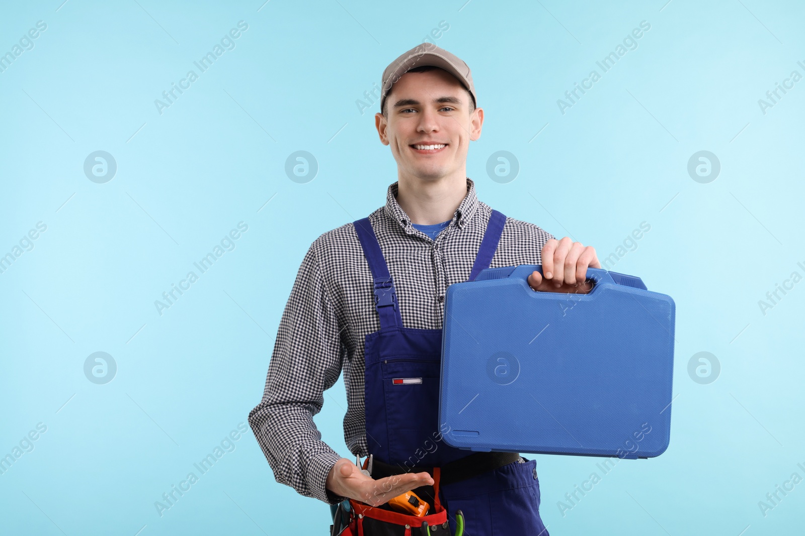 Photo of Professional repairman with tool box on light blue background