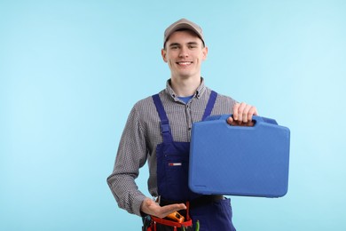 Professional repairman with tool box on light blue background