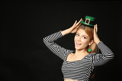 Photo of Young woman with green leprechaun hat on black background, space for text. St. Patrick's Day celebration