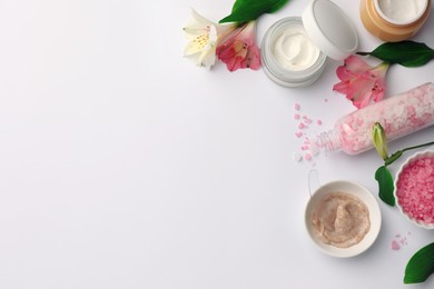 Flat lay composition with different spa products and beautiful flowers on white table. Space for text