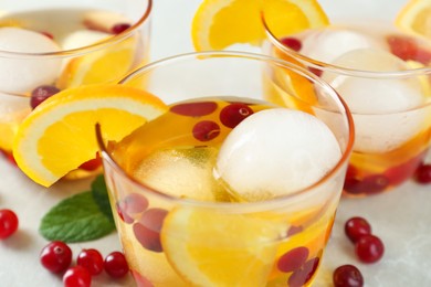 Photo of Delicious cocktails with orange, cranberries and ice balls on light grey marble table, closeup