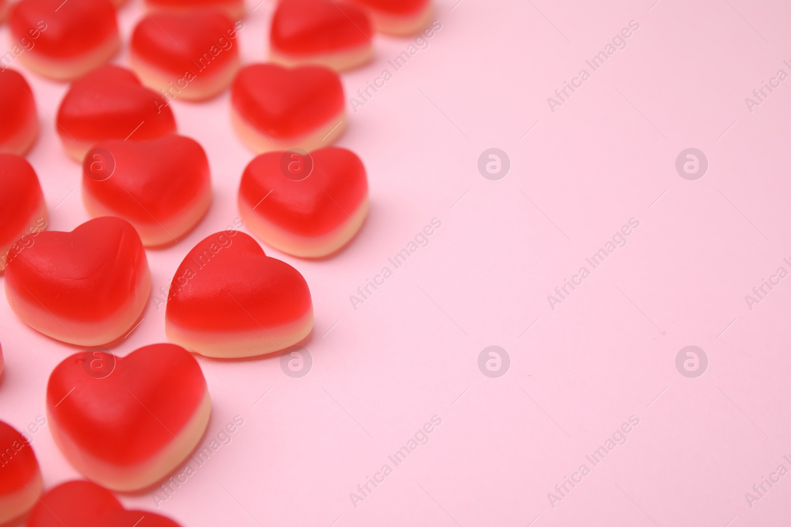 Photo of Delicious heart shaped jelly candies on pink background, closeup. Space for text