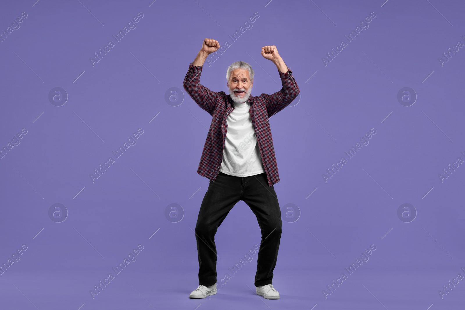 Photo of Happy senior sports fan celebrating on purple background