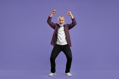 Photo of Happy senior sports fan celebrating on purple background