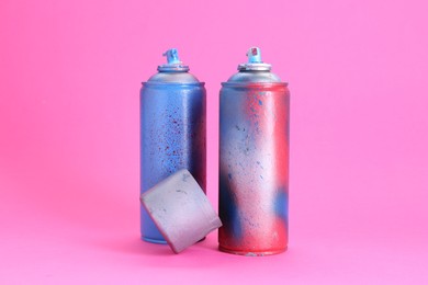 Photo of Spray paint cans with cap on pink background