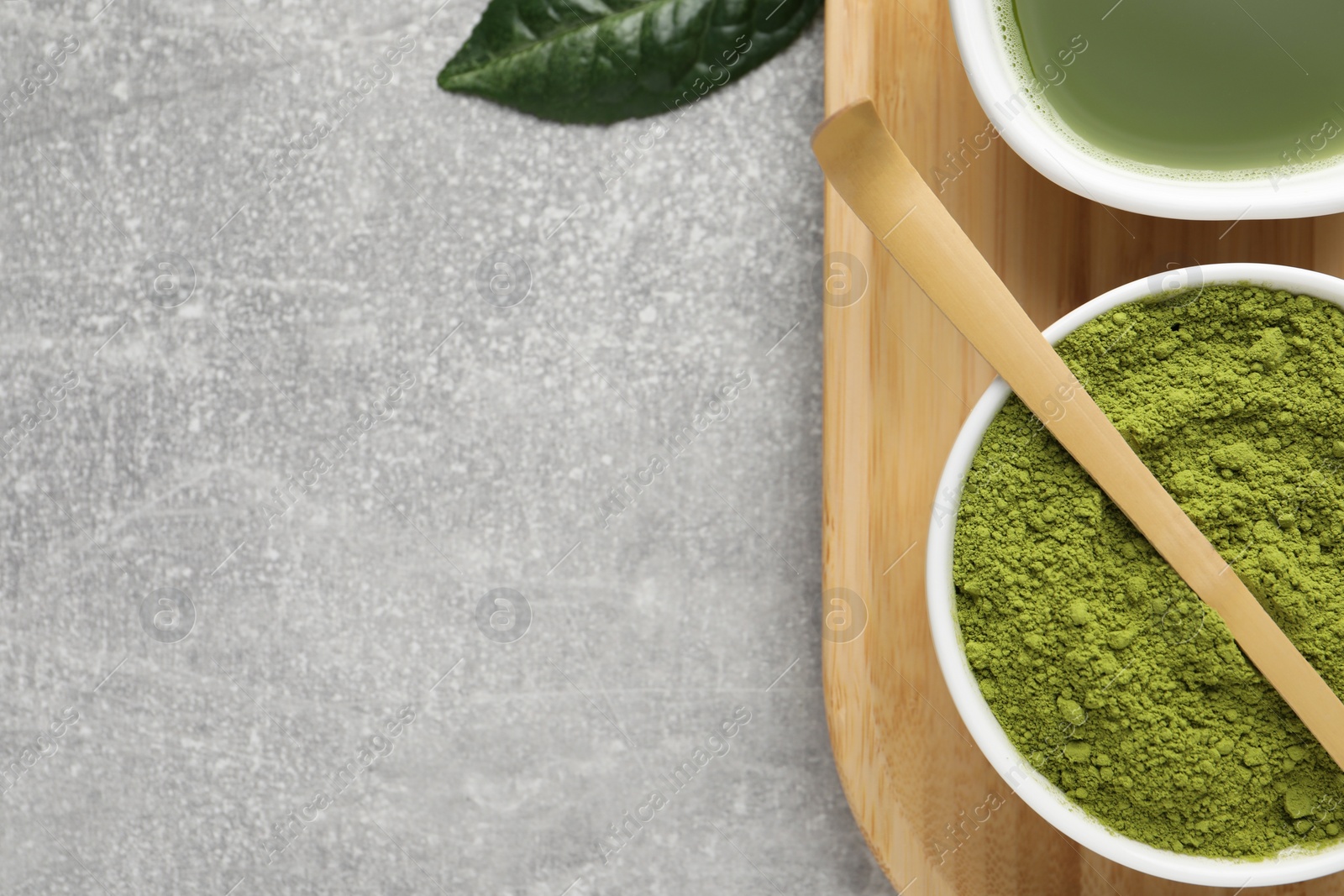 Photo of Green matcha powder, bamboo scoop and fresh beverage on light grey table, flat lay. Space for text