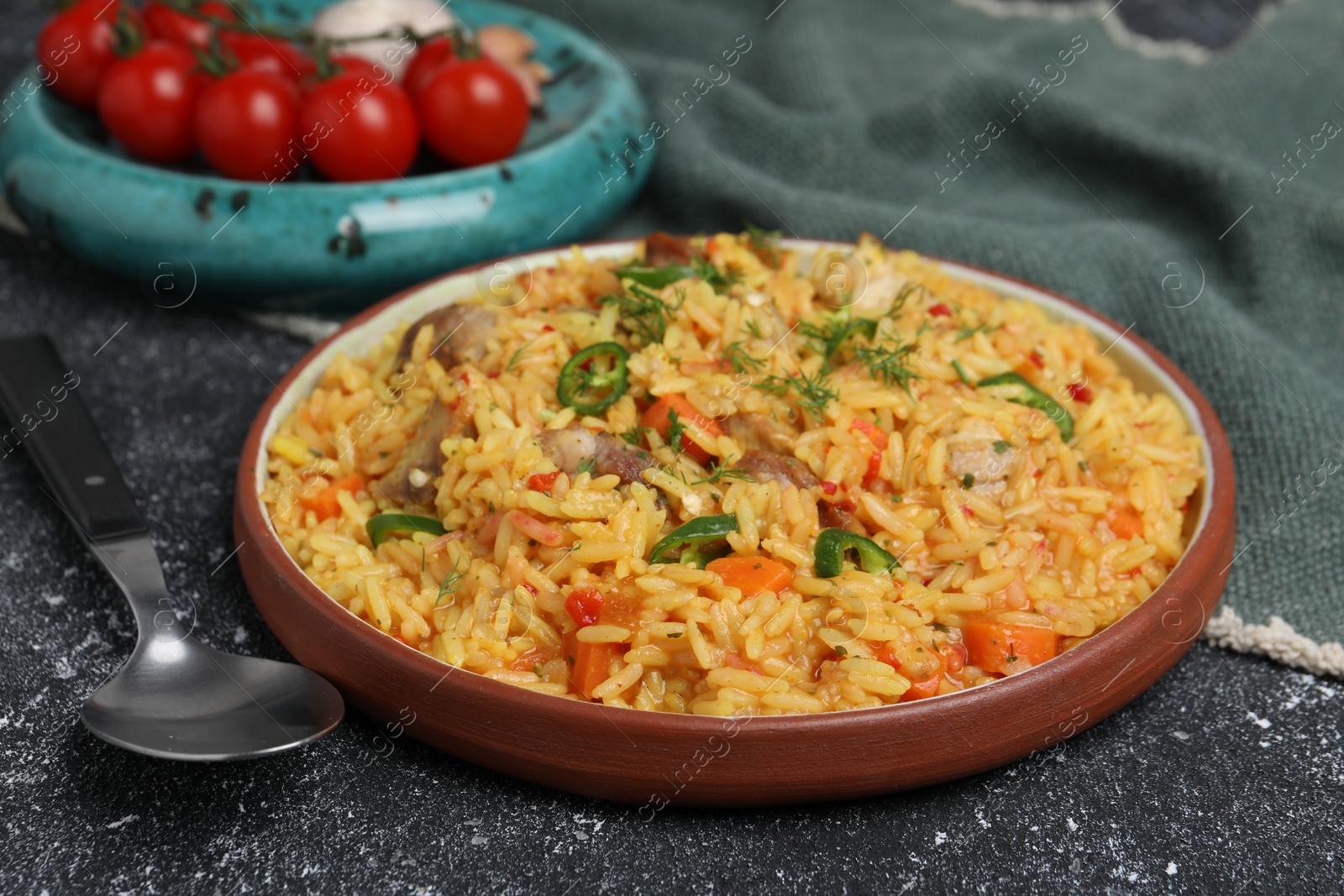 Photo of Delicious pilaf with meat served on black textured table, closeup