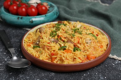 Photo of Delicious pilaf with meat served on black textured table, closeup