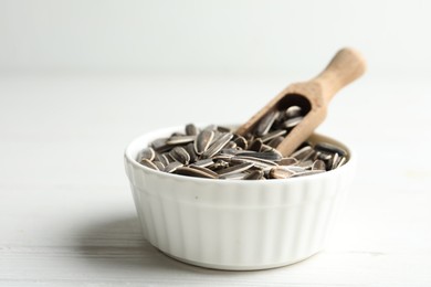 Photo of Organic sunflower seeds on white wooden table, closeup