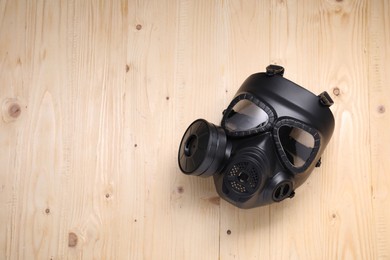 Photo of One gas mask on wooden background, top view. Space for text