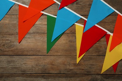 Photo of Buntings with colorful triangular flags on wooden background, space for text