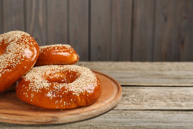 Photo of Delicious fresh bagels with sesame seeds on wooden table, closeup. Space for text