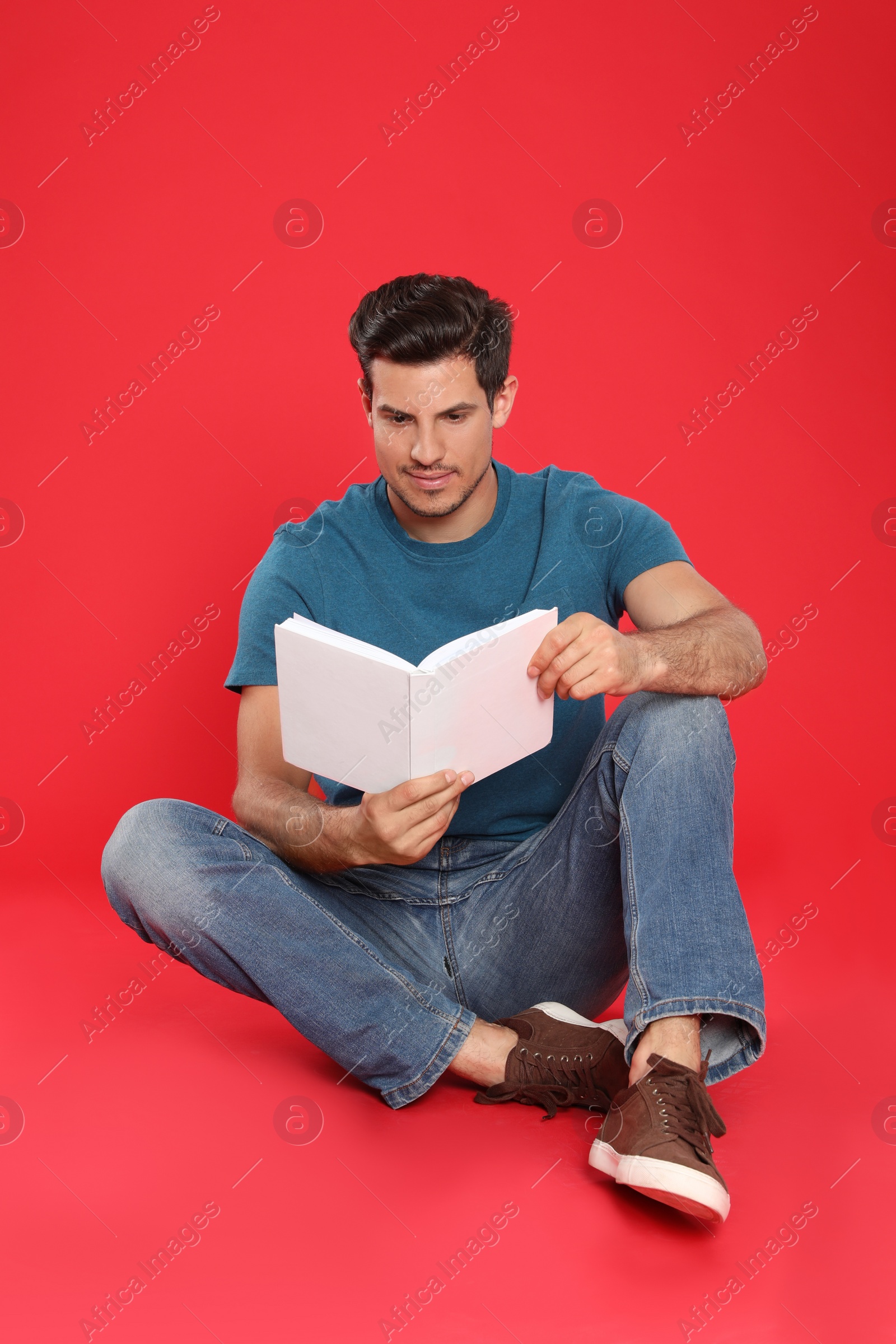 Photo of Handsome man reading book on color background, space for text