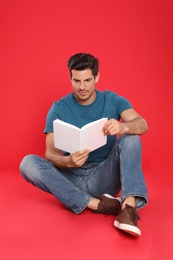 Photo of Handsome man reading book on color background, space for text