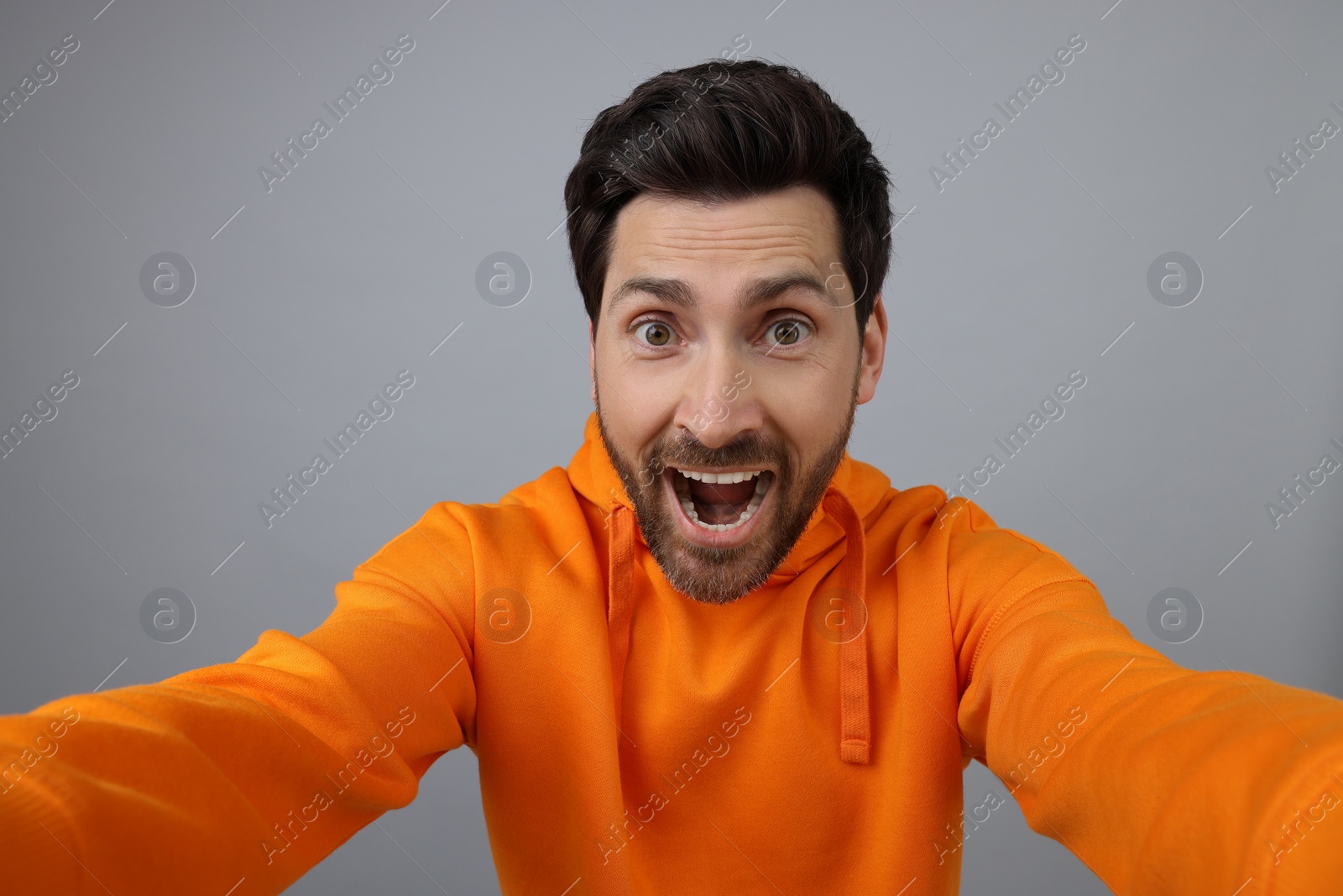 Photo of Happy man taking selfie on grey background
