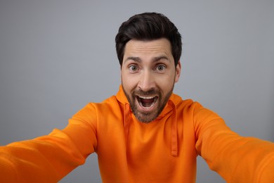 Photo of Happy man taking selfie on grey background