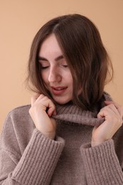 Photo of Portrait of beautiful young woman in warm sweater on brown background