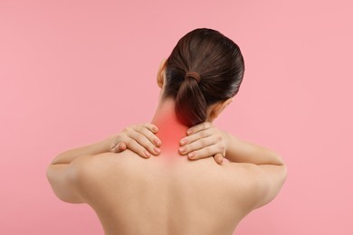 Woman suffering from neck pain on pink background, back view