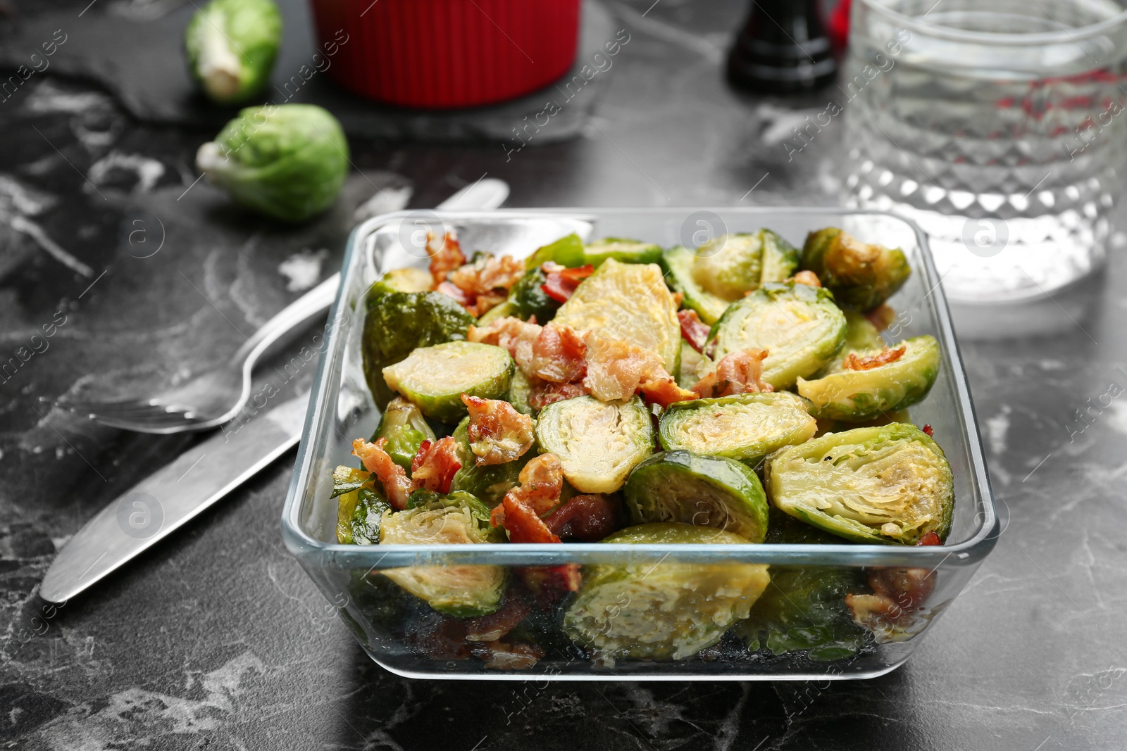 Photo of Delicious cooked Brussels sprouts with bacon served on marble table