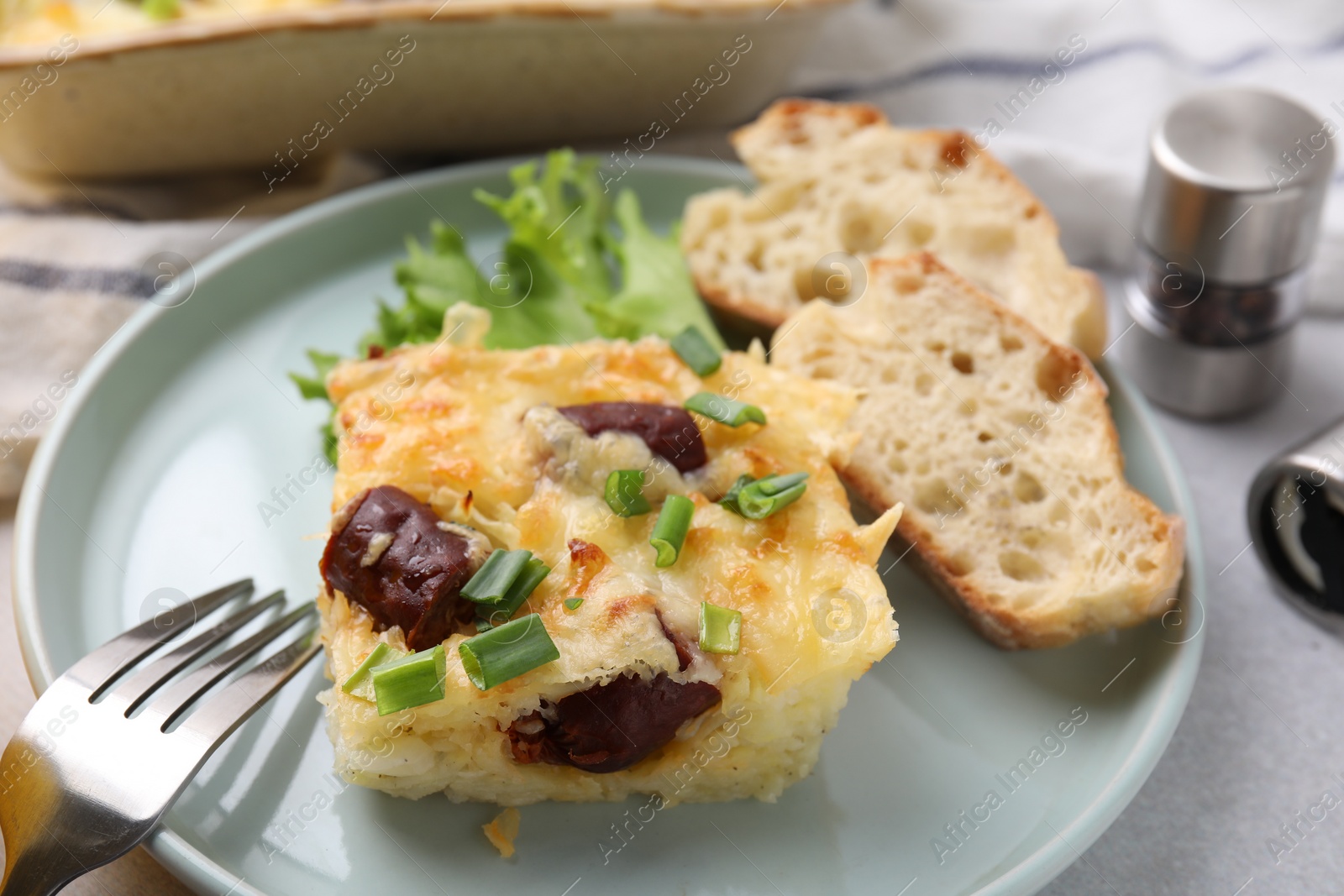 Photo of Tasty sausage casserole served on light grey table, closeup