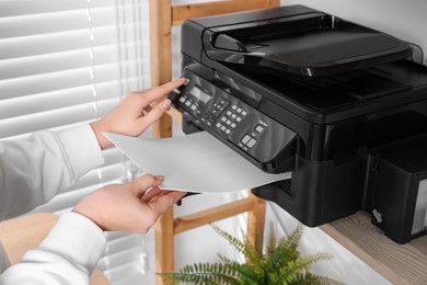 Photo of Woman loading paper into printer on shelf indoors, closeup