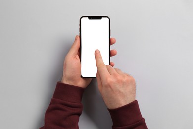 Man using smartphone on light grey background, top view