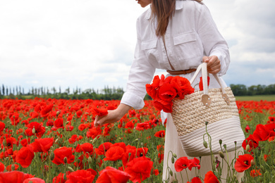 Photo of Woman with handbag picking poppy flowers in beautiful field, closeup