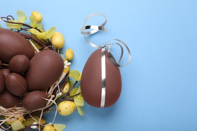 Photo of Delicious chocolate eggs on light blue background, flat lay. Space for text