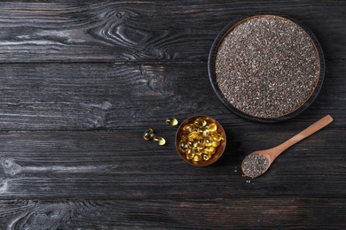 Flat lay composition with chia seeds and oil capsules on dark wooden background. Space for text