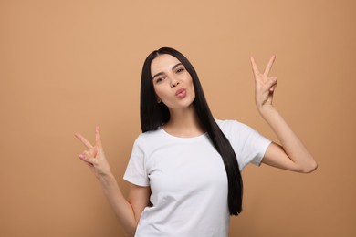 Beautiful young woman blowing kiss on beige background