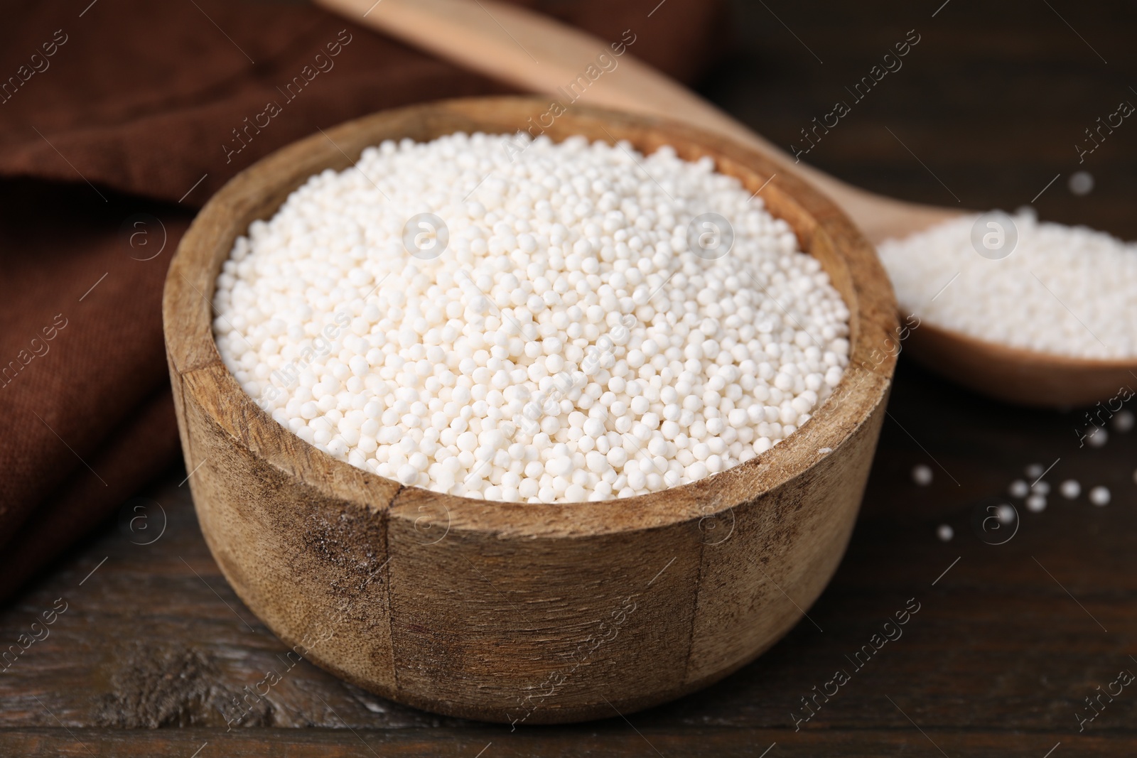 Photo of Tapioca pearls in bowl on wooden table, closeup